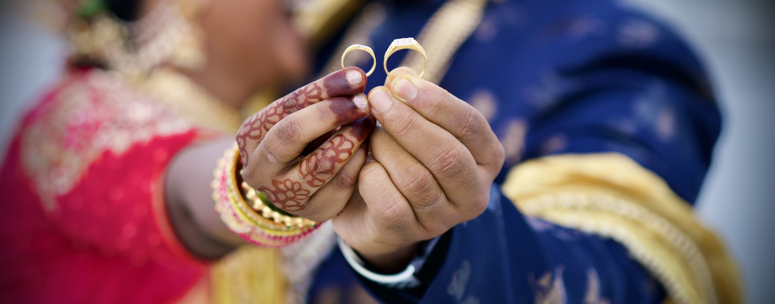 shallow focus of a bride and groom raising rings during traditional wedding ceremony in